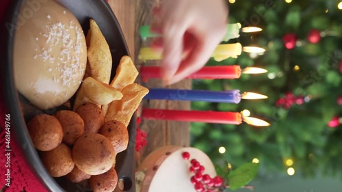 Candlelight Day. Typical food. Buñuelo, natilla and hojuelas with candles and Christmas tree in the background. Traditional Colombian holiday. Vertical video.