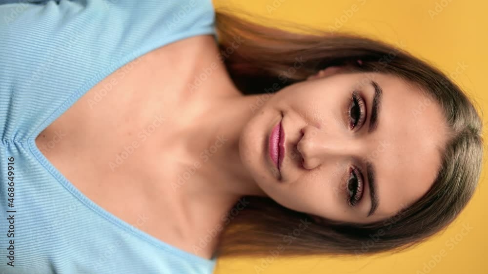 VERTICAL VIDEO POV closeup face of tired young woman feeling head neck pain posing isolated orange VERTICAL VIDEO POV closeup face of tired young woman feeling head neck pain posing isolated orange
