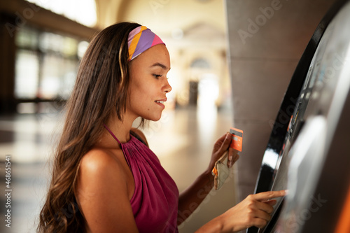 Happy smiling young woman withdrawing money from credit card. Young woman using ATM machine.