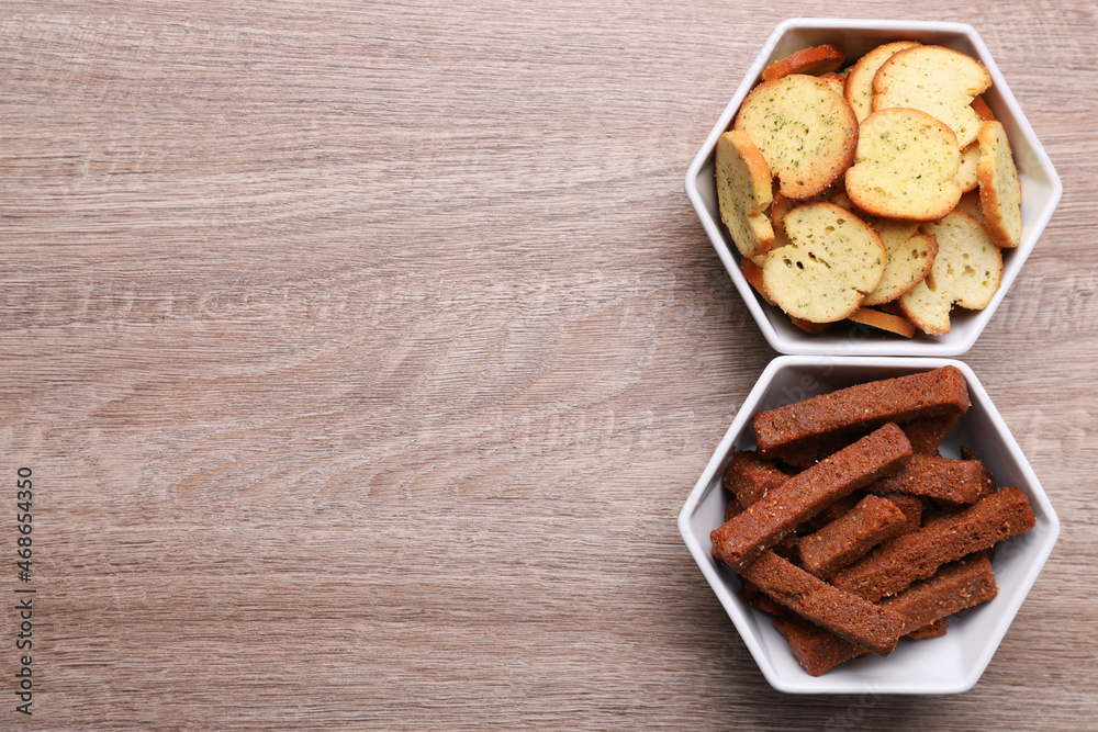 Different crispy rusks in bowls on wooden table, flat lay. Space for text Different crispy rusks in bowls on wooden table, flat lay. Space for text