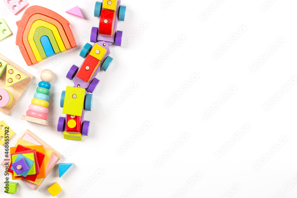 Baby kids toys background. Top view to wooden toy train, wood stacking pyramid tower and colorful wood bricks on white background. Early education, zero waste, Montessori toys for children