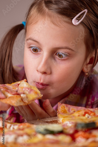 Funny portrait of young beautiful attractive girl eat street food pizza. Selective focus on eyes. Vertical image.