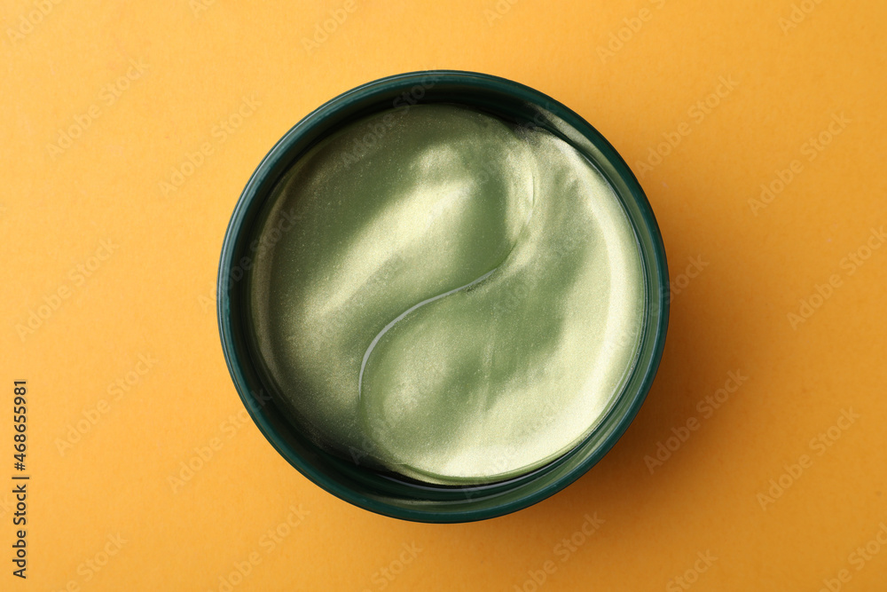 Under eye patches in jar on orange background, top view. Cosmetic product Under eye patches in jar on orange background, top view. Cosmetic product