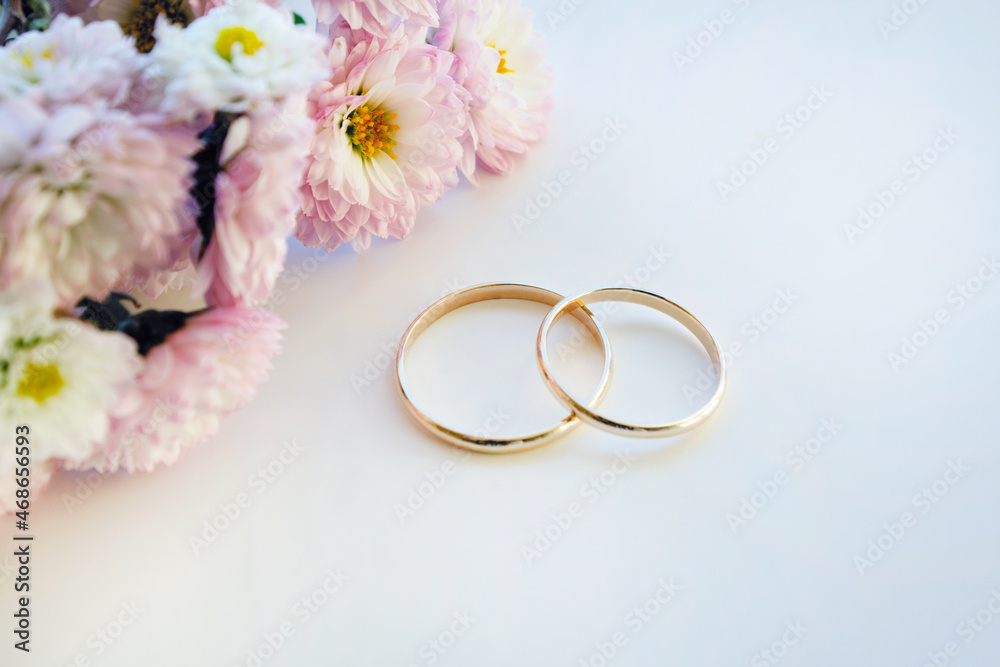 A pair of gold wedding rings with bridal flowers on white background A pair of gold wedding rings with bridal flowers on white background