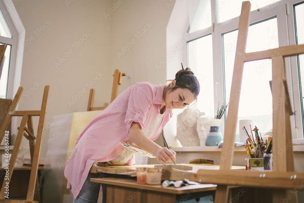 Female artist working in studio. Creative workspace, painting class, easel with canvas, art therapy. Inspiration, creativity, talent, craft concept. Artist studio interior. People, leisure and hobby