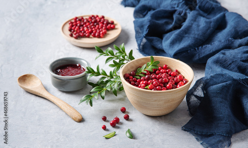 juicy forest lingonberry with handmade jam in a wooden bowl on white table with blue napkin. Concept homemade healthy food. Close up