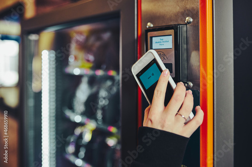 Woman paying for product at vending machine using smartphone photo