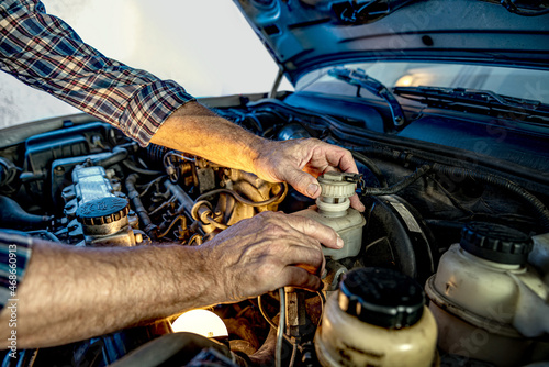 Repairman's male hands with a wrench. Vehicle fitter inspecting used car engine