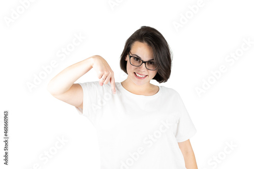 Studio shot on isolated white background of young girl with dark straight hair in t-shirt pointing finger down