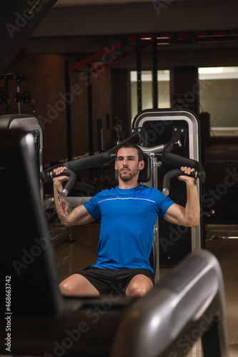 young man exercising lats on machine