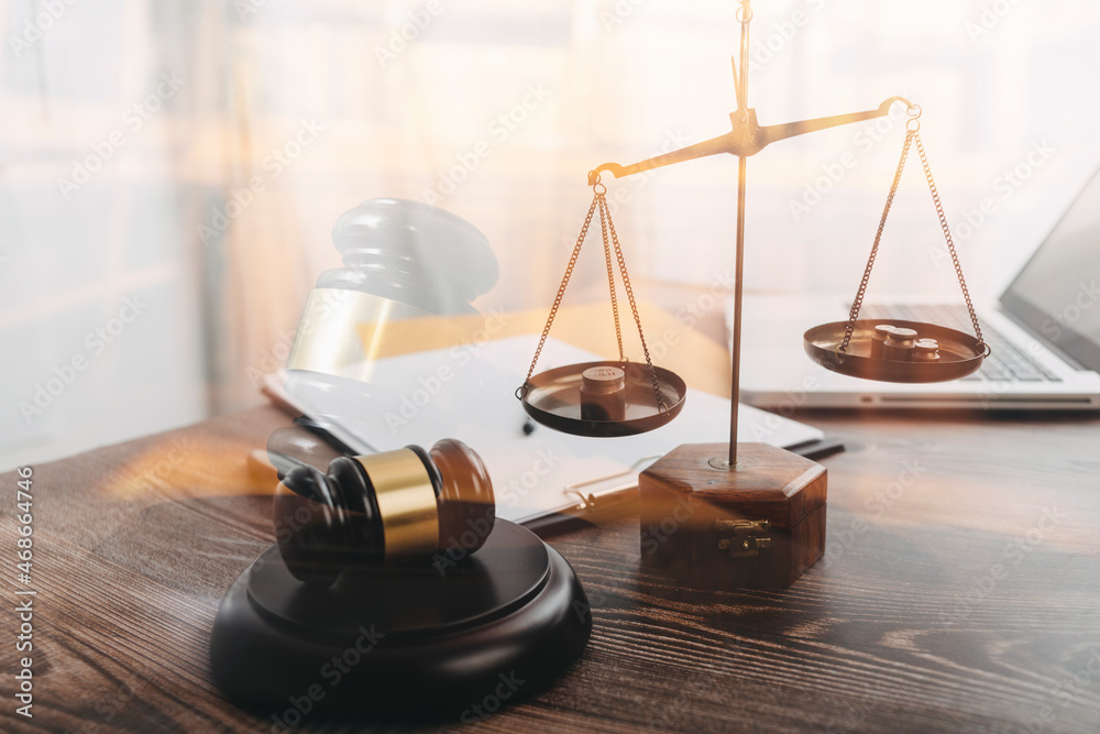 Justice and law concept.Male judge in a courtroom with the gavel, working with, computer and docking keyboard, eyeglasses, on table in morning light Justice and law concept.Male judge in a courtroom with the gavel, working with, computer and docking keyboard, eyeglasses, on table in morning light