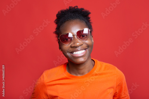 Portrait of a positive African woman in sunglasses on a red background  © Alexandr
