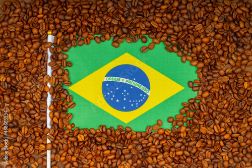 Roasted coffee beans and Brazilian flag on the table. Brazilian Coffee price rise concept. Arabica Coffee Futures Climb from Brazil. Top view. Close-up
