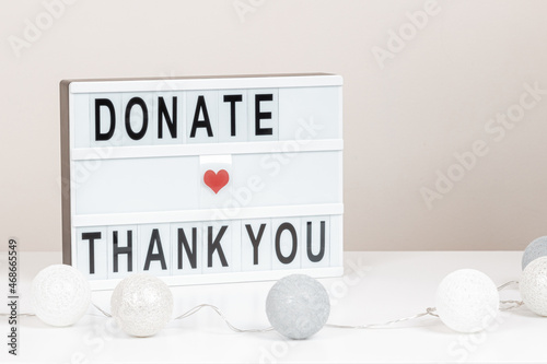 Christmas donation, charity. White lightbox with message Donate and Thank you standing on the table. Front view, close up