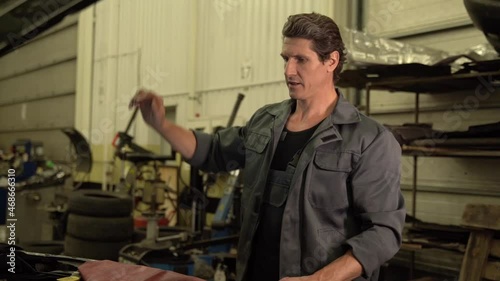 Video shot of the serious adult auto mechanic opening hood of the car while preparing to the repair. Car service concept