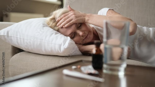 Sick sad woman lies on the couch at home. A middle-aged caucasian unhealthy woman is lying on a sofa , she feeling bad, headache, illness, need a rest and treatment