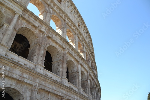 coliseum in rome italy showing old architecture in brown tones with blue sky, outside of coliseum
