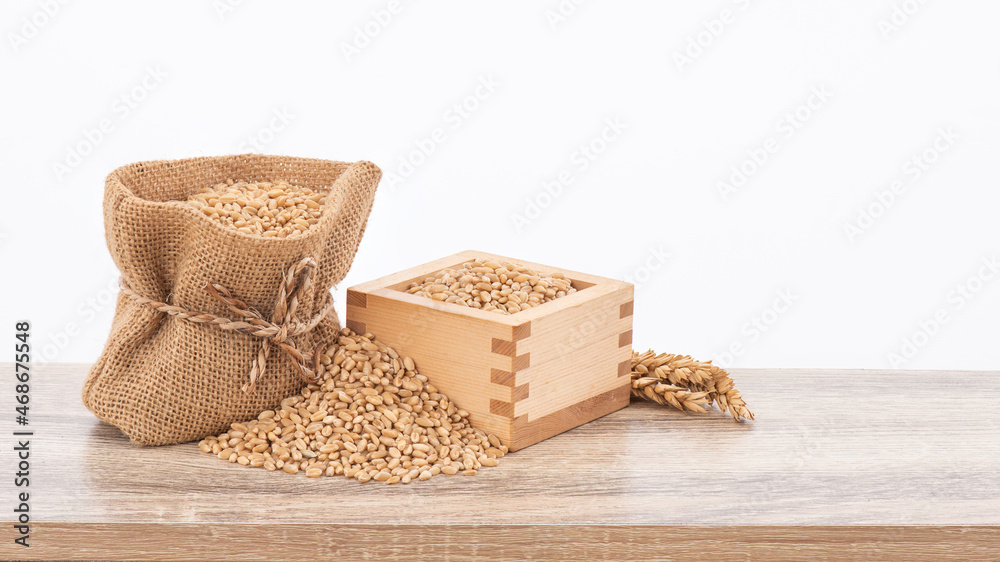 Wheat or Triticum aestivum wheat kernel on wood table isolated on white background with clipping path. Wheat or Triticum aestivum wheat kernel on wood table isolated on white background with clipping path.