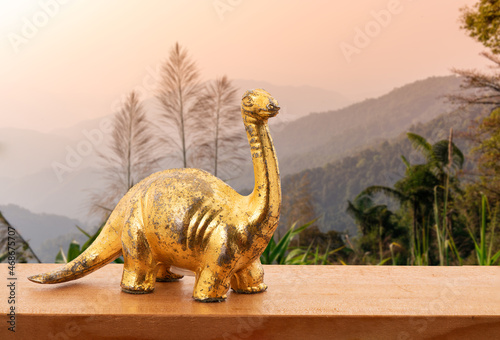 Fototapeta Naklejka Na Ścianę i Meble -  Old gold dinosaur on wood table and on nature background.