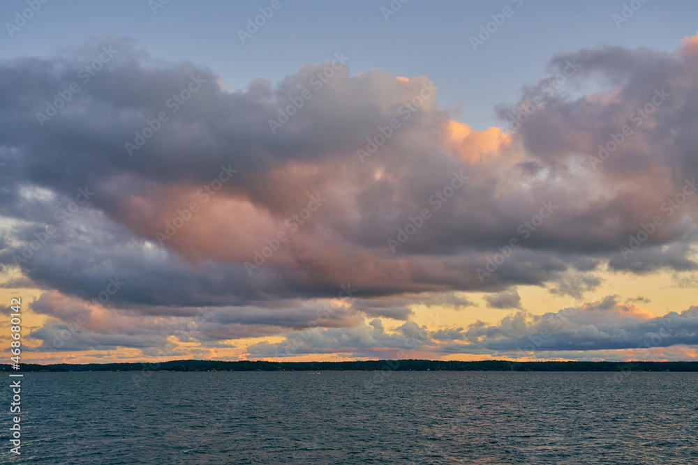 A colorful sunset on the Baltic Sea with clouds illuminated by the sun setting over the horizon.