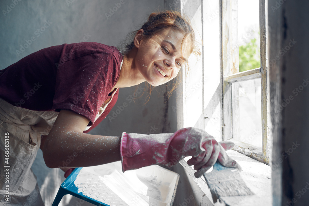 woman with brush paints window sill at home near window interior renovation woman with brush paints window sill at home near window interior renovation