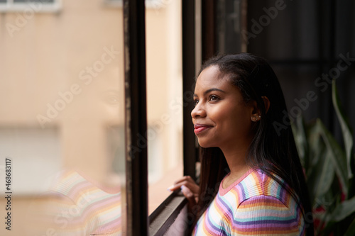 Tableau sur toile Smiling African American girl near the window looking out.