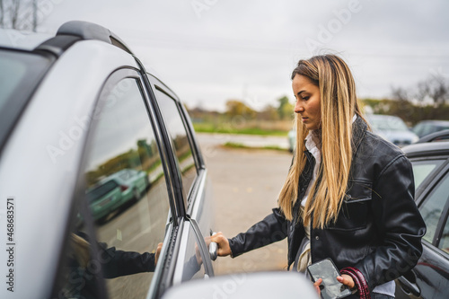Side view one young caucasian woman opening or closing car door in autumn day