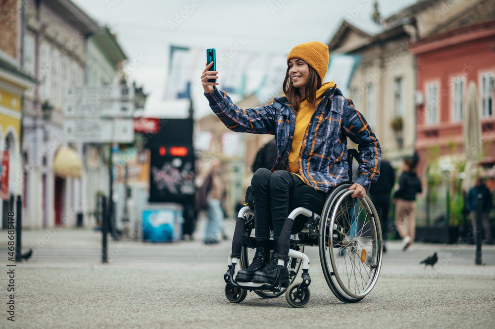 Obraz premium Woman with disability taking a selfie with her smartphone while out in the city