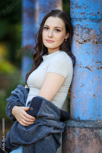 Beautiful teenage girl leans against a purple pillar.  photo