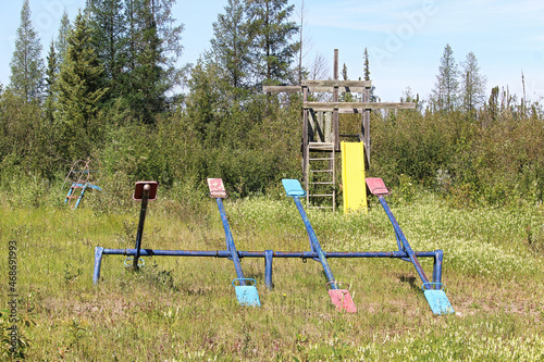 An unmaintained playground with overgrown grass photo