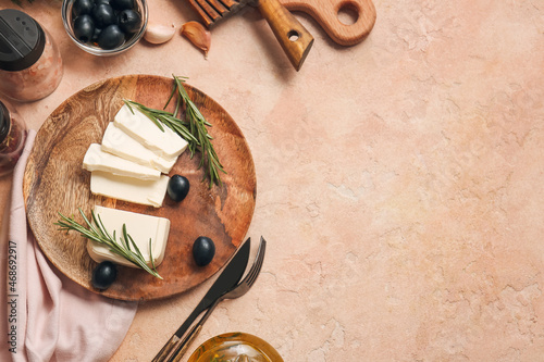 Plate with delicious feta cheese with rosemary and olives on color background