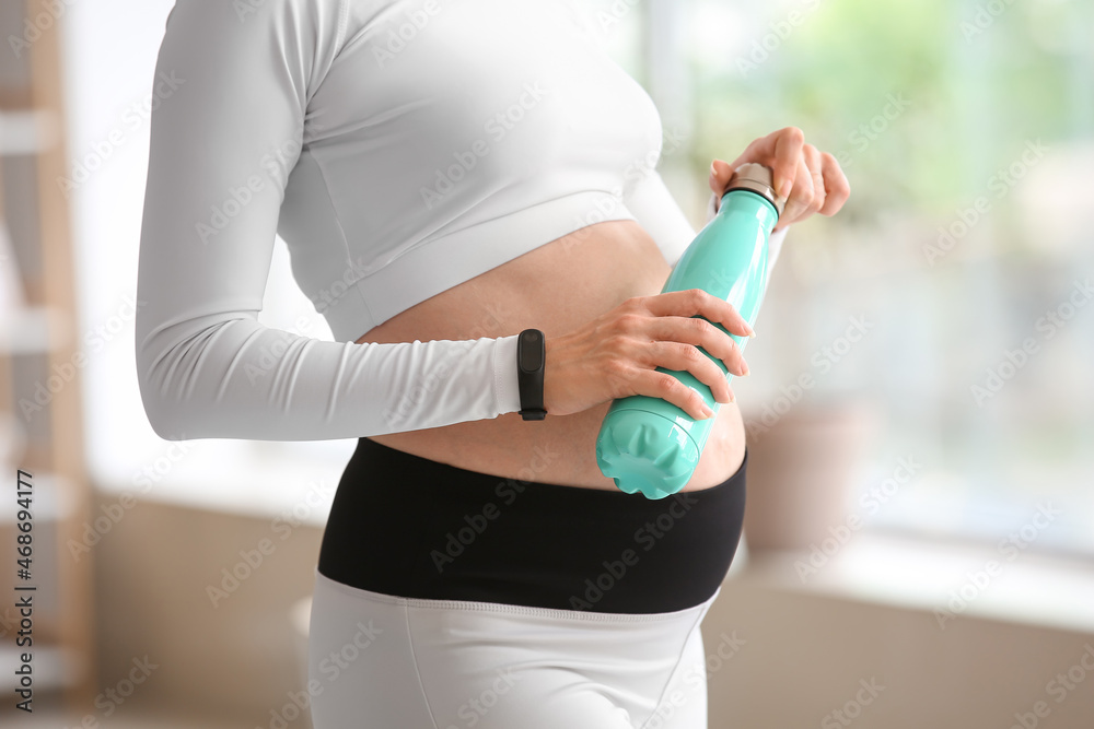Young pregnant woman with bottle of refreshing water in gym Young pregnant woman with bottle of refreshing water in gym