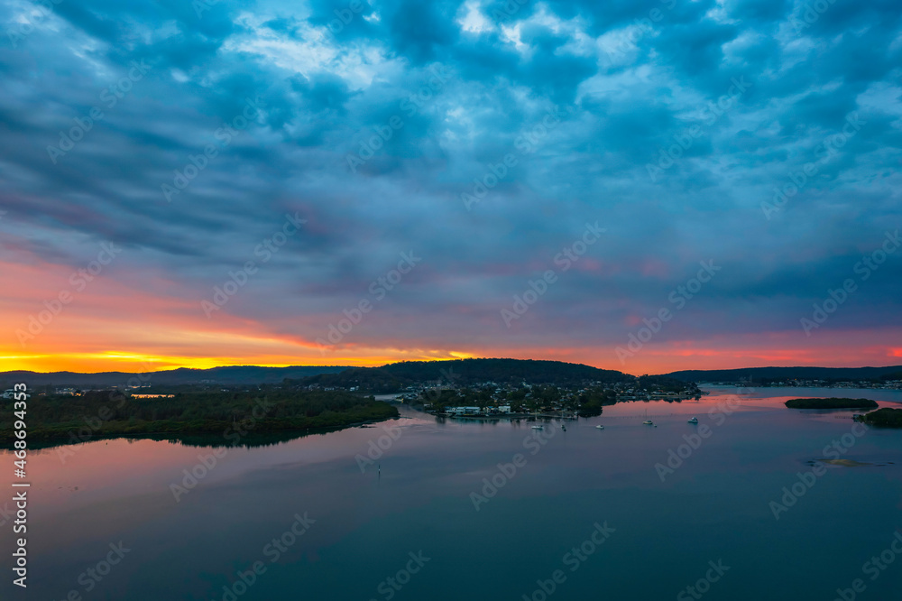 Sunrise waterscape with colourful cloud covered sky