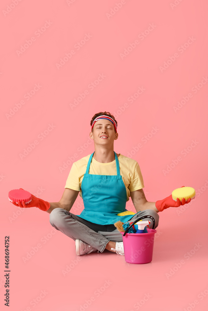 Handsome man with cleaning sponges meditating on pink background Handsome man with cleaning sponges meditating on pink background