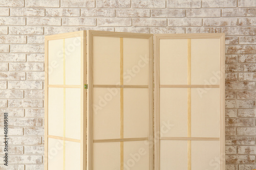 Beige folding screen near light brick wall