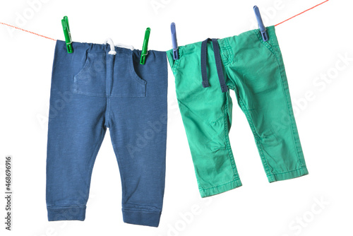 Baby pants hanging on rope with clothespins against white background