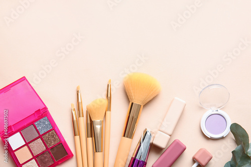 Set of decorative cosmetics with makeup brushes on color background