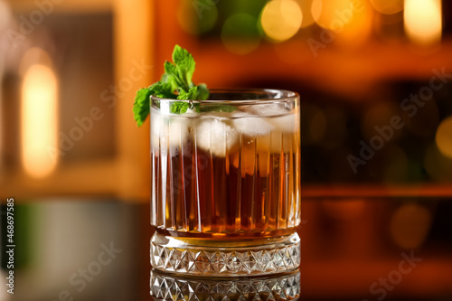 Photography Glass of tasty Cuba Libre cocktail with mint on table in bar