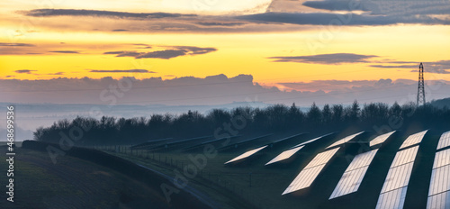 Solar energy park and conventional electricity pylon at sunset,Hampshire,England,UK.