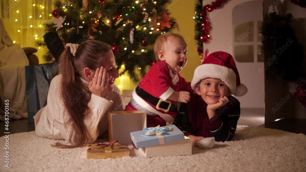 Cute baby boy playing with brother and mother on Christmas eve. Families and children celebrating winter holidays. Cute baby boy playing with brother and mother on Christmas eve. Families and children celebrating winter holidays.
