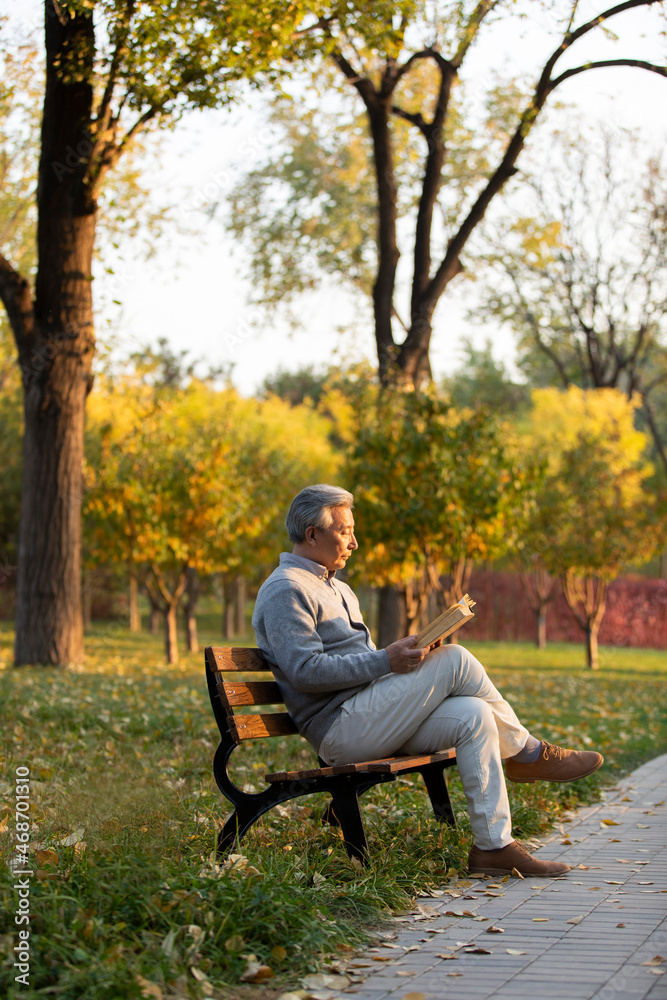 Senior Chinese man reading book in the park Senior Chinese man reading book in the park