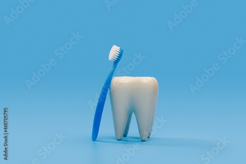 big tooth and blue toothbrush for kids isolated on a blue background with copy space, dental care concept.