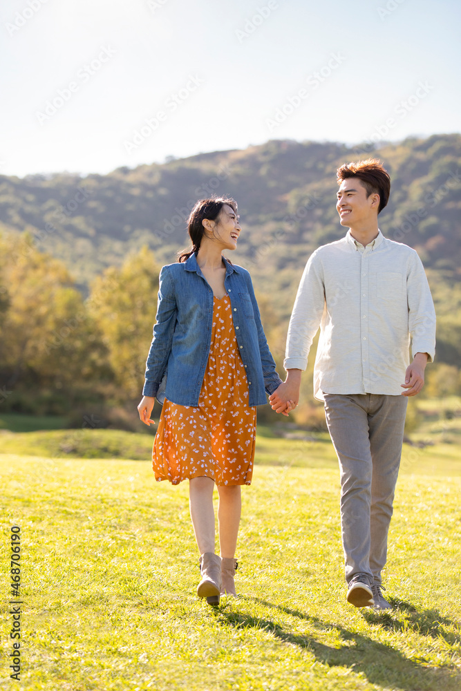 Happy young Chinese couple holding hands walking Happy young Chinese couple holding hands walking
