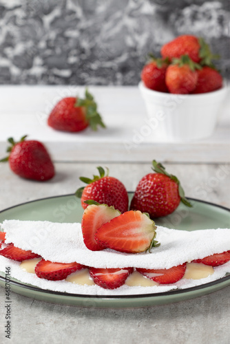 Selective focus on Brazilian tapioca with strawberry and condensed milk.