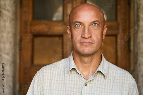 Bald man, dressed in casual shirt on, was amazed and surprised, looking at the camera with blue eyes. Emotional intent facial expression