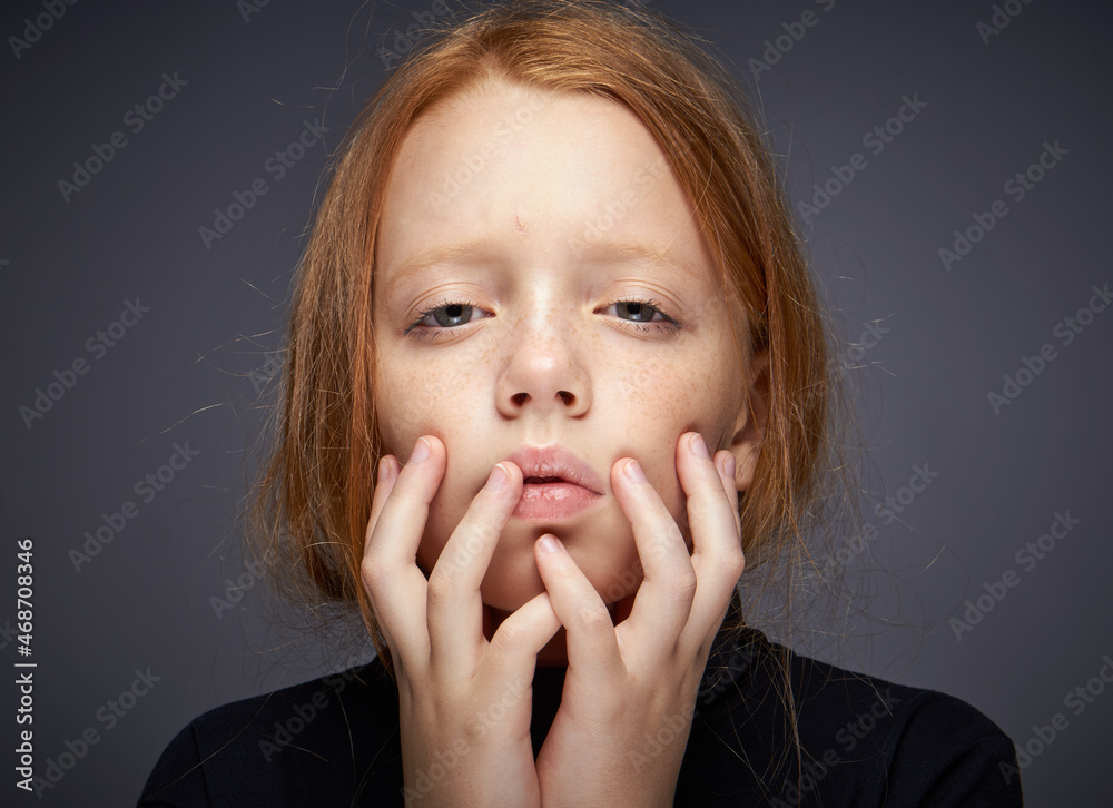 red-haired girl with freckles on her face in a black sweater posing red-haired girl with freckles on her face in a black sweater posing