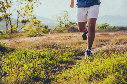 Young man running over on the mountain workout outdoors in summer.