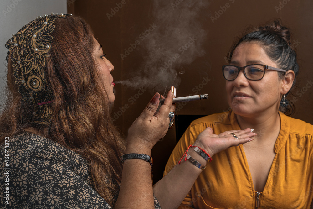 Fototapeta premium Woman blowing cigarette smoke at another woman's face, ritual