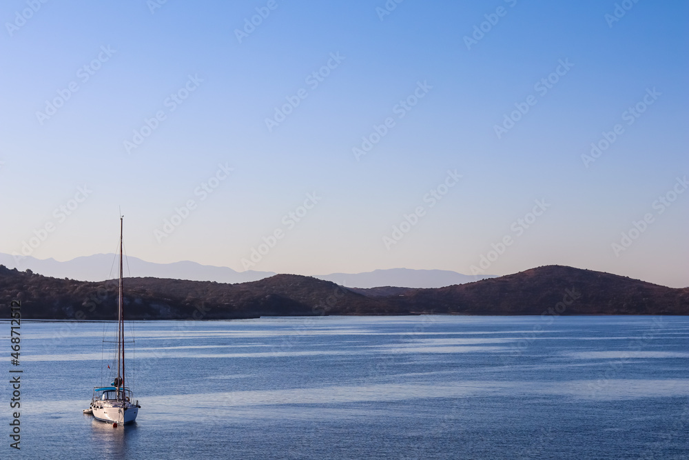 Blue sea, a boat and mountains in sunrise. Tranquil seascape and coastal nature concept