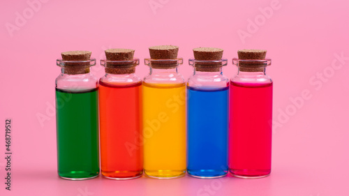 Liquid of different colors are poured into glass bottles with wooden corks